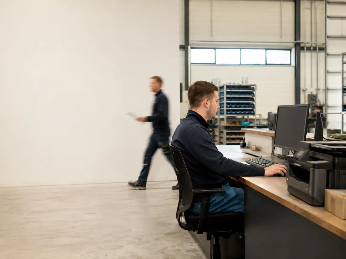 Binnendienstmedewerker werkt aan een werkstation in de bedrijfshal